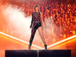 An image of Taylor Swift standing in front of the audience during her performance in Eras Tour.