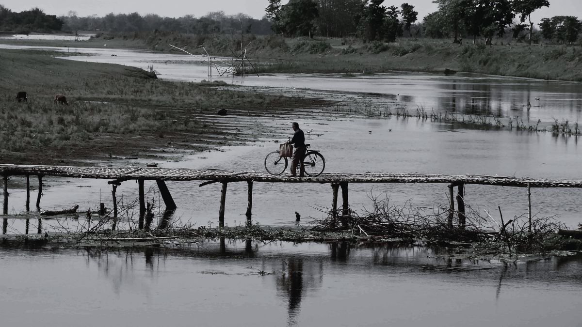 A person cycling on a bridge made by wood as a part of the every day Majuli Life.