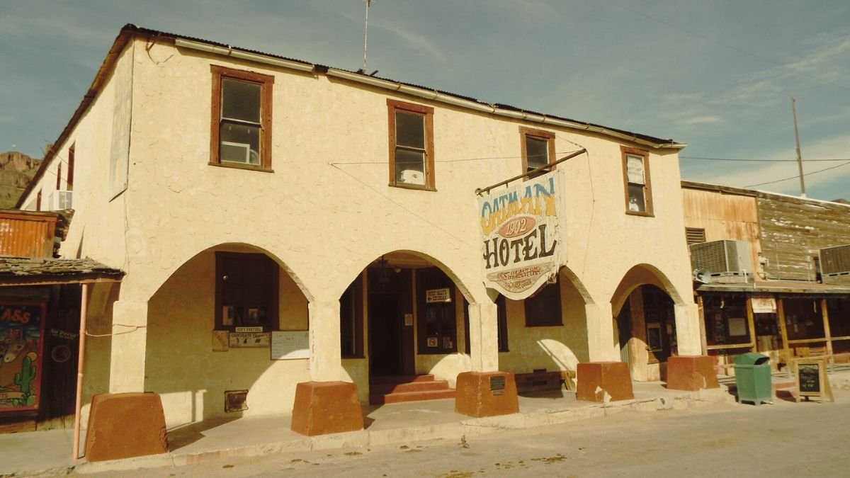 An old hotel in front of the road with a signboard mentioning Oatman hotel